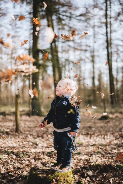 young boy laughing under falling leaves autumn perfectionism