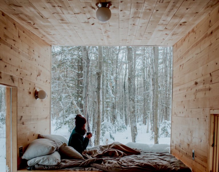 cozy winter with woman holding a mug looking out onto a wintry landscape