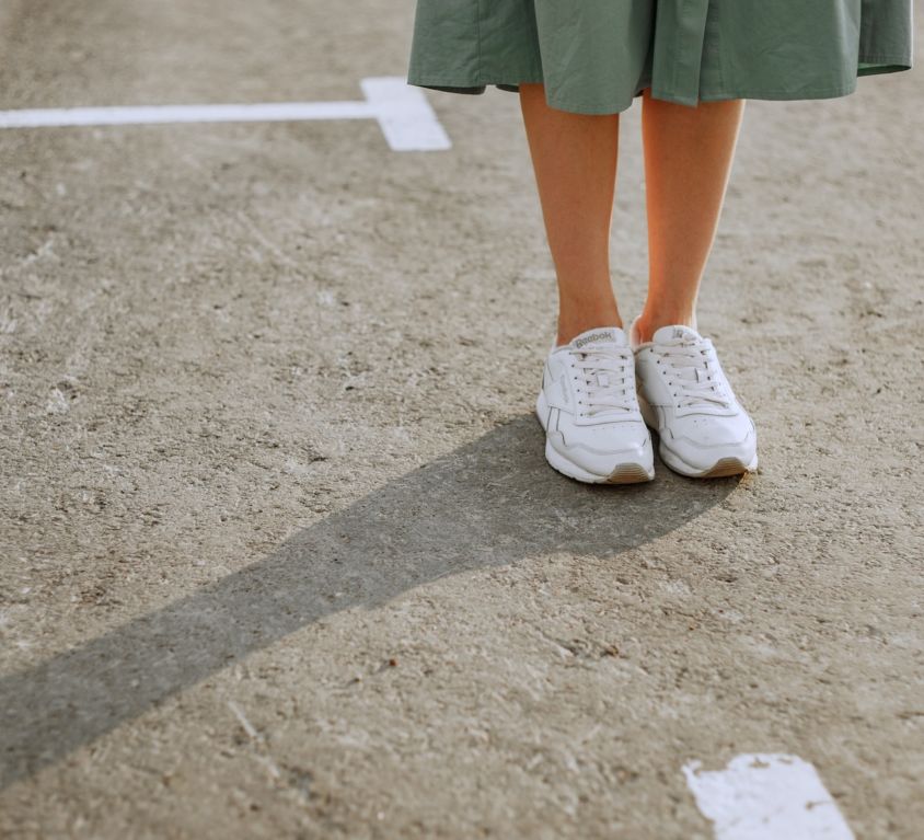 girl in a green skirt standing in white sneakers